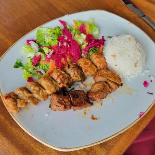 Cinar Restaurant's Mediterranean plate with grilled meat skewers, rice, and a vibrant salad.