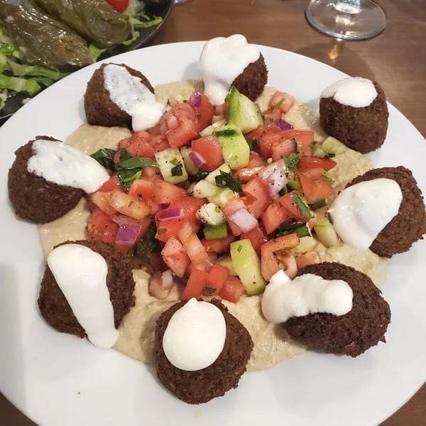 Cinar Restaurant's falafel plate with hummus, tomato and cucumber salad, and creamy white sauce.